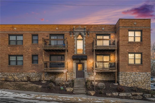 view of property with brick siding and a balcony