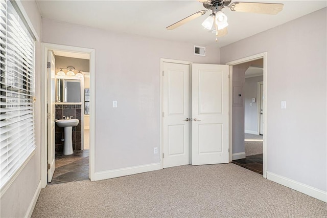 unfurnished bedroom featuring ensuite bathroom, carpet, ceiling fan, and a closet