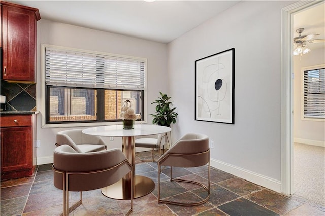dining room with baseboards, a ceiling fan, and stone tile floors