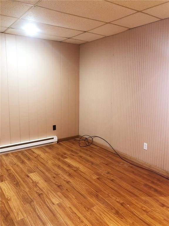 spare room featuring a drop ceiling, light hardwood / wood-style flooring, and baseboard heating