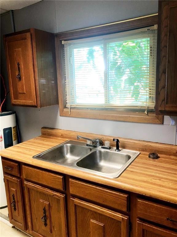 kitchen featuring sink, water heater, and light tile patterned floors