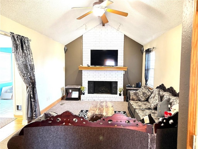 living room featuring lofted ceiling, ceiling fan, a fireplace, and a textured ceiling