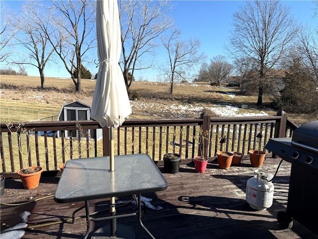 wooden deck with a shed and a grill