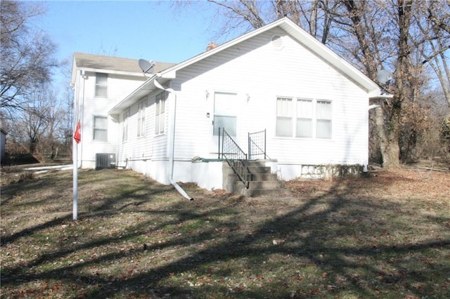 back of house featuring a lawn and central air condition unit