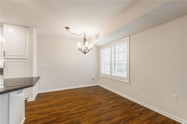 unfurnished dining area with an inviting chandelier and dark wood-type flooring