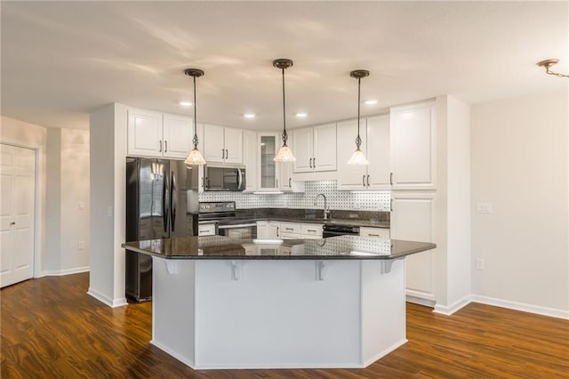 kitchen featuring appliances with stainless steel finishes, hanging light fixtures, backsplash, white cabinets, and a kitchen island