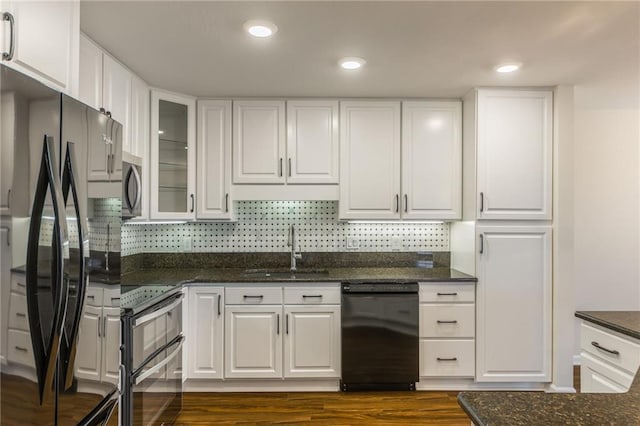 kitchen with sink, dark stone countertops, white cabinets, and black appliances