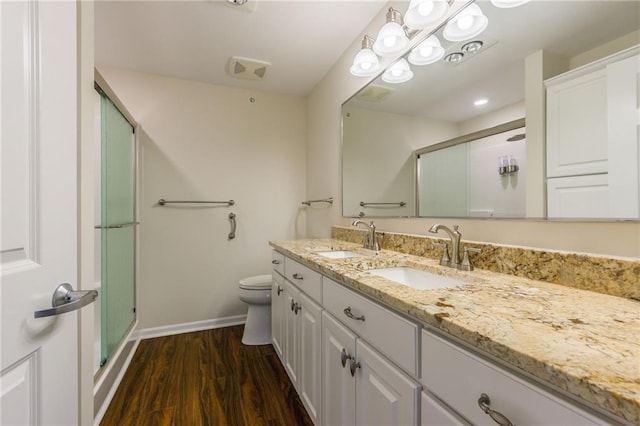 bathroom featuring vanity, hardwood / wood-style floors, a shower with shower door, and toilet