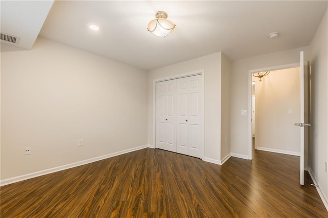 unfurnished bedroom with dark wood-type flooring and a closet