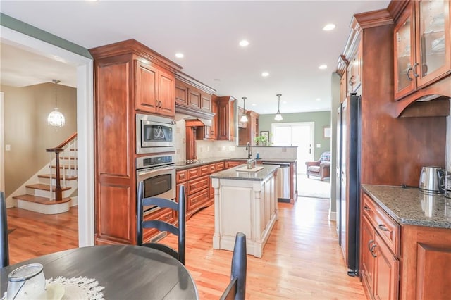 kitchen with sink, hanging light fixtures, stainless steel appliances, kitchen peninsula, and dark stone counters