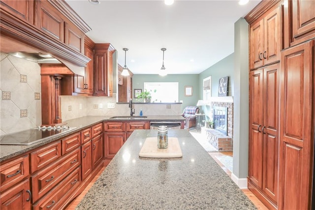 kitchen with pendant lighting, dark stone counters, sink, and black electric cooktop