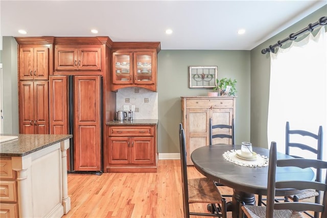 kitchen with decorative backsplash, light wood-type flooring, and dark stone counters