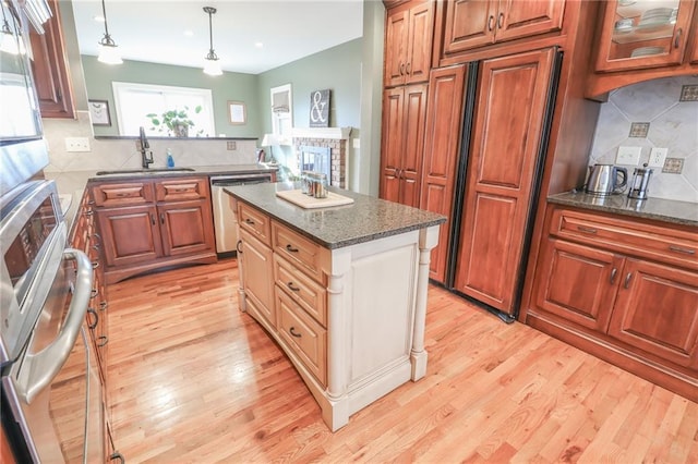 kitchen featuring sink, a center island, light hardwood / wood-style floors, decorative light fixtures, and stainless steel dishwasher