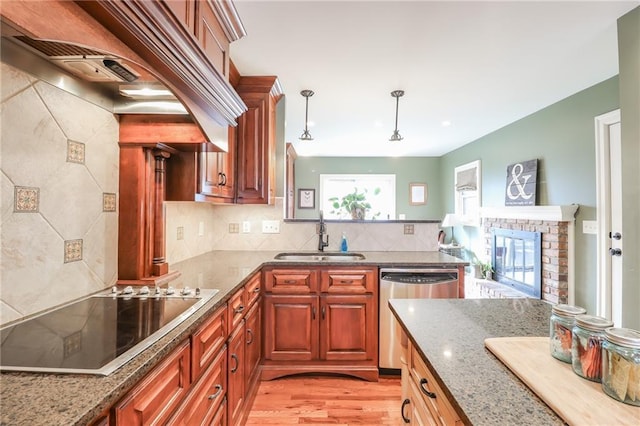 kitchen with sink, light stone counters, black electric cooktop, decorative light fixtures, and stainless steel dishwasher