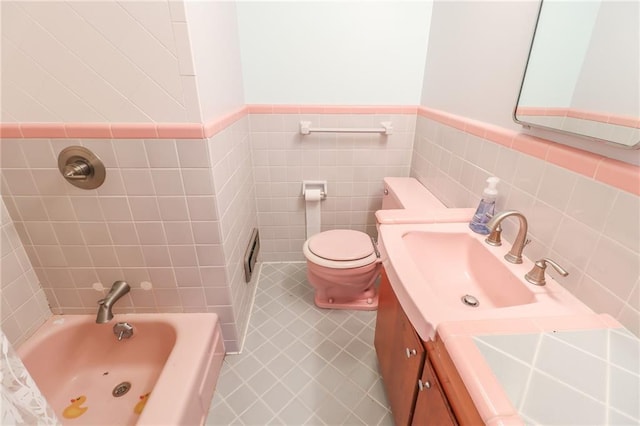 bathroom featuring toilet, tile walls, vanity, a bathtub, and tile patterned flooring