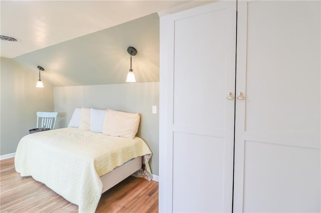 bedroom featuring lofted ceiling and light wood-type flooring