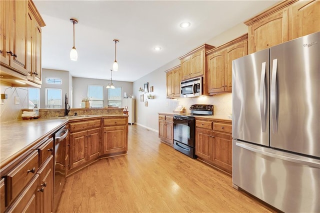 kitchen featuring hanging light fixtures, stainless steel appliances, light hardwood / wood-style floors, backsplash, and sink