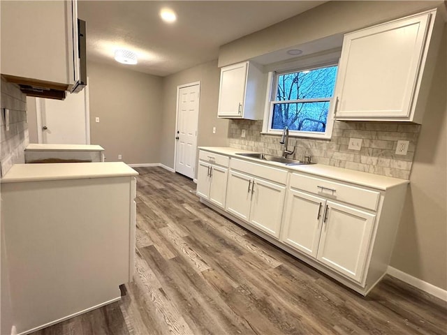 kitchen with backsplash, sink, hardwood / wood-style floors, and white cabinets