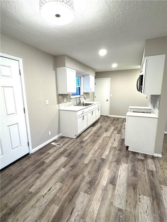 kitchen with sink, white cabinets, decorative backsplash, stove, and dark wood-type flooring