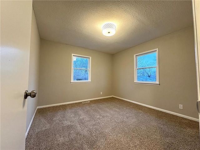 carpeted spare room with a textured ceiling