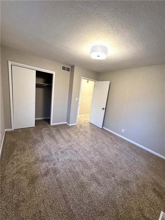 unfurnished bedroom with carpet floors, a closet, and a textured ceiling