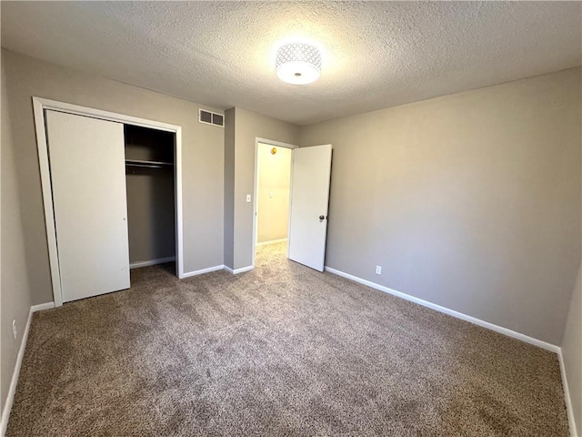 unfurnished bedroom featuring carpet, a textured ceiling, and a closet