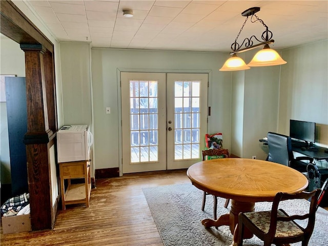 dining area with ornate columns, hardwood / wood-style floors, and french doors