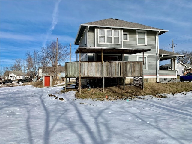 snow covered rear of property featuring covered porch