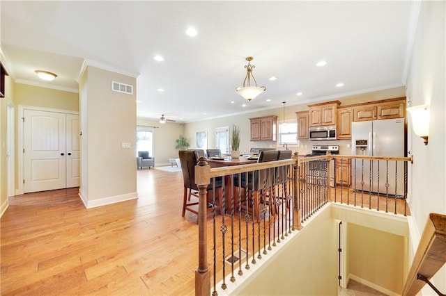 interior space with light wood-style floors, visible vents, and ornamental molding