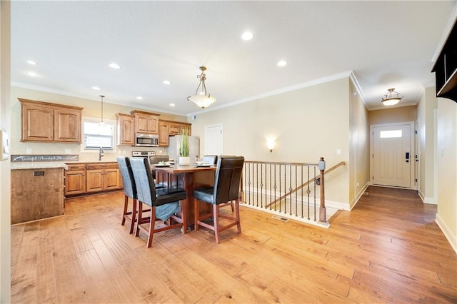 dining space with light wood-style floors, recessed lighting, ornamental molding, and baseboards