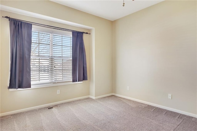 empty room featuring carpet, a wealth of natural light, and baseboards