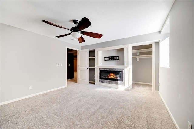 unfurnished living room featuring light carpet, ceiling fan, a fireplace, and baseboards