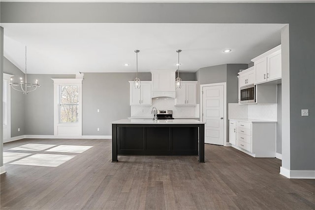 kitchen featuring tasteful backsplash, white cabinets, dark hardwood / wood-style flooring, a kitchen island with sink, and stainless steel appliances