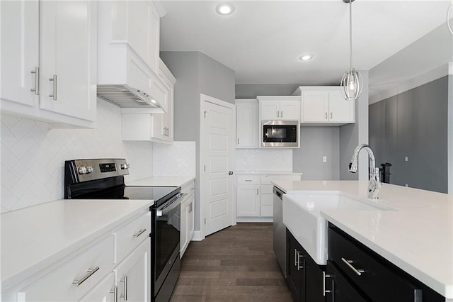 kitchen featuring dark wood-type flooring, sink, decorative light fixtures, appliances with stainless steel finishes, and white cabinets