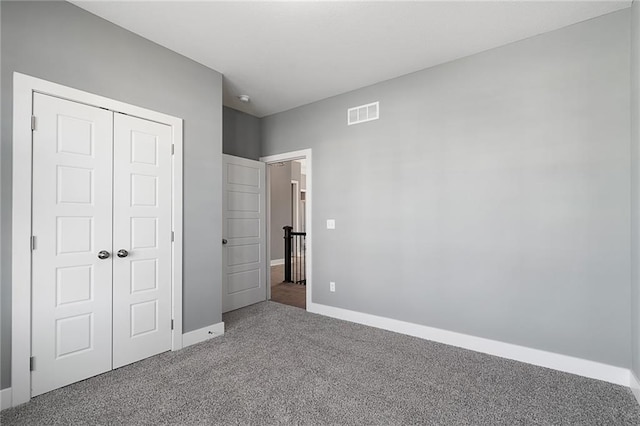 unfurnished bedroom with a closet and dark colored carpet