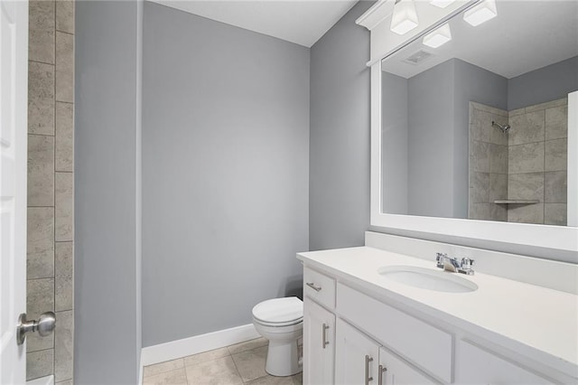 bathroom with tile patterned flooring, vanity, tiled shower, and toilet