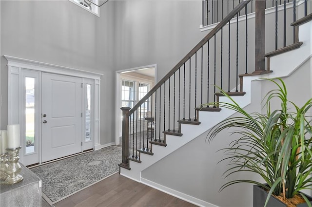 foyer entrance with a towering ceiling and dark wood-type flooring