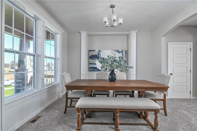 carpeted dining area with an inviting chandelier, a textured ceiling, and a wealth of natural light