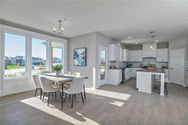 dining room featuring an inviting chandelier, sink, and light hardwood / wood-style floors