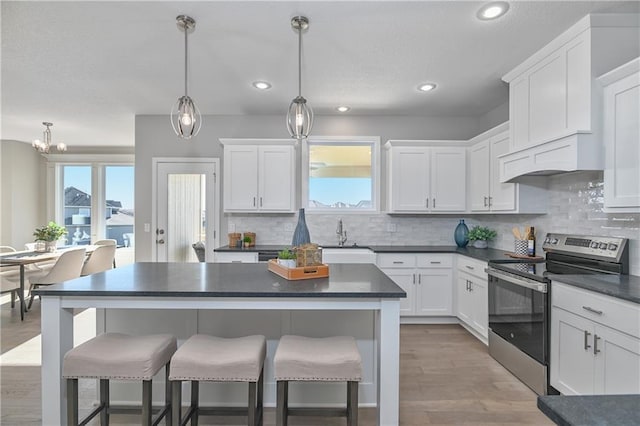 kitchen with white cabinetry, decorative light fixtures, sink, and stainless steel electric range