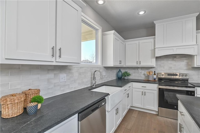 kitchen featuring sink, hardwood / wood-style flooring, appliances with stainless steel finishes, white cabinets, and decorative backsplash