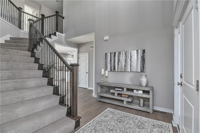 stairs with hardwood / wood-style floors and a high ceiling