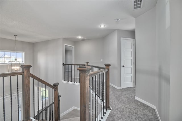 hallway featuring a chandelier and carpet