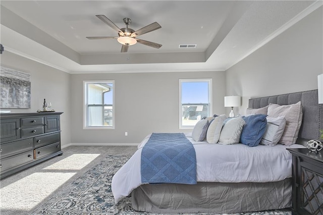 carpeted bedroom featuring a raised ceiling and ceiling fan