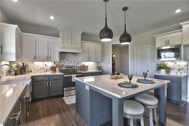 kitchen featuring pendant lighting, sink, stainless steel appliances, white cabinets, and decorative backsplash