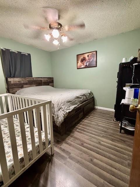 bedroom featuring ceiling fan, wood-type flooring, and a textured ceiling