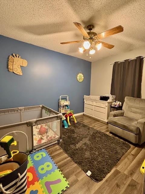 recreation room with hardwood / wood-style flooring, ceiling fan, and a textured ceiling