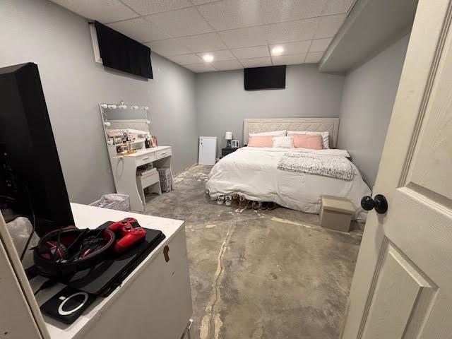 bedroom with concrete floors and a drop ceiling