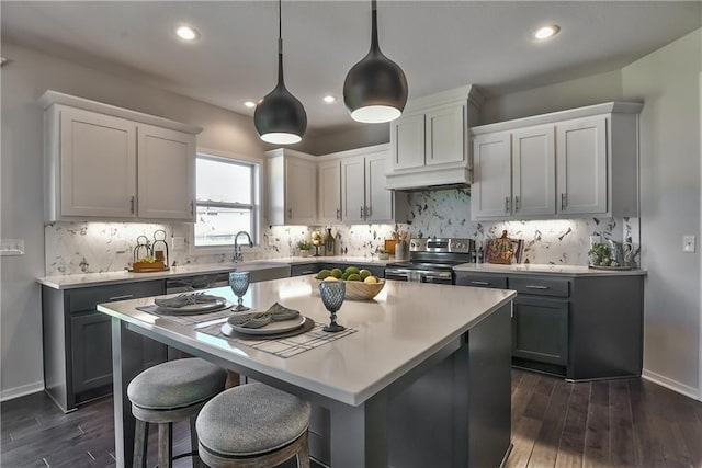 kitchen featuring sink, tasteful backsplash, decorative light fixtures, stainless steel electric range, and a kitchen island