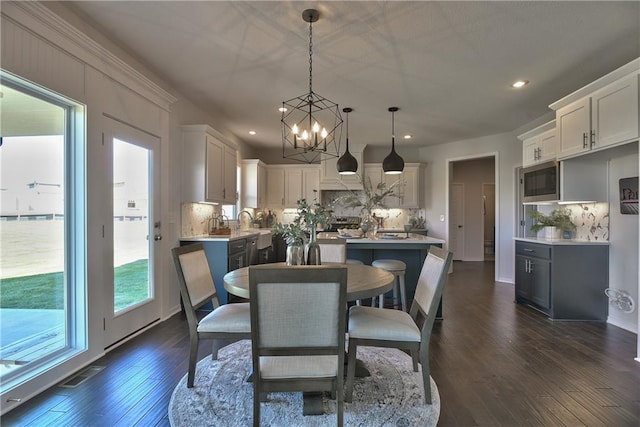 dining space featuring sink, dark wood-type flooring, and a chandelier